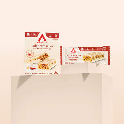 Two packages of Atkins high protein bars on a beige background