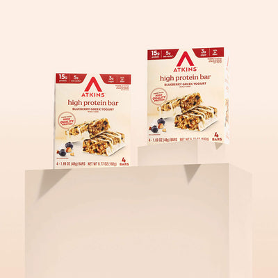 Two boxes of Atkins high protein bars on a beige background