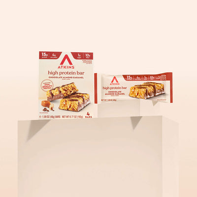 Two packages of Atkins high protein bars on a beige background
