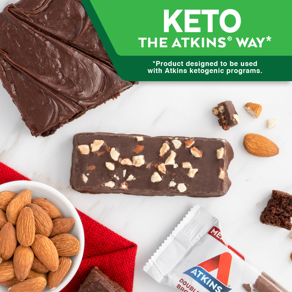 Double Fudge Brownie Bar  with almond and chocolate next to it on a marble table; Keto The Atkins Way* *Product designed to be used with Atkins ketogenic programs.
